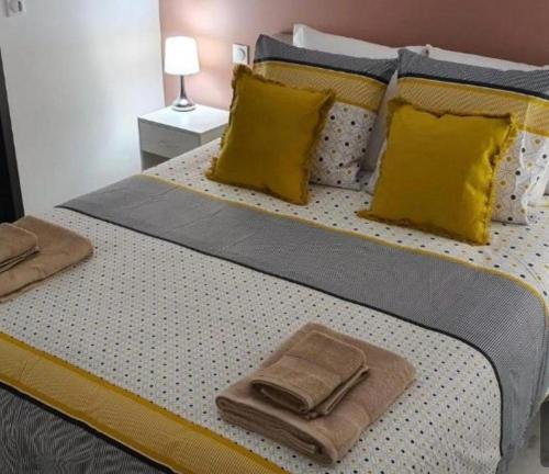- un lit avec des oreillers et des serviettes jaunes dans l'établissement Villa les chênes, à Unzent