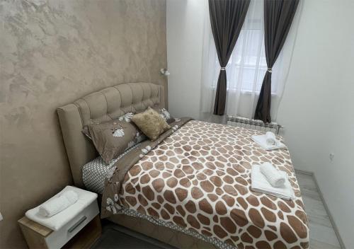 a bedroom with a bed with a brown bedspread and a window at Apartman Manda 2 in Belgrade