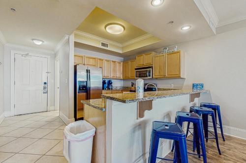 a kitchen with a counter with stools and a refrigerator at Holiday Isle 603 in Dauphin Island