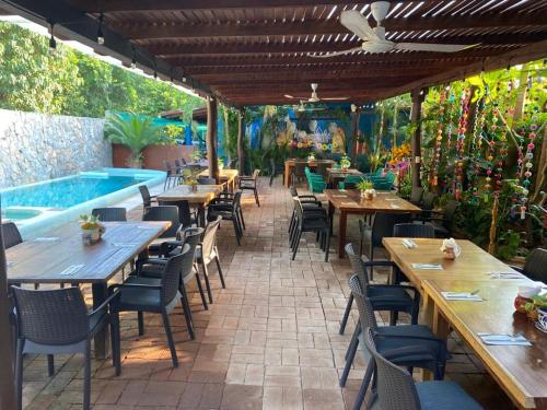 a restaurant with tables and chairs and a swimming pool at Hotel Restaurante Mi Jardin Troncones in Troncones