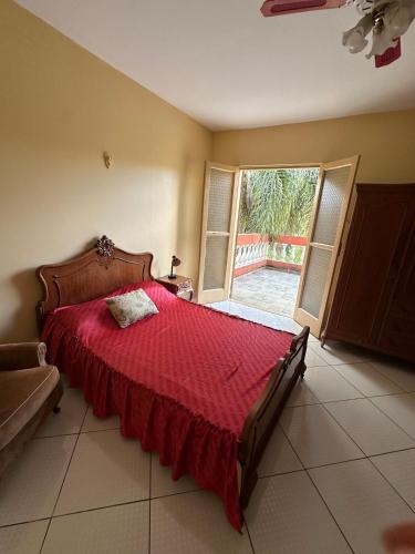 a bedroom with a large bed with a red bedspread at Recanto Paraíso in Cotia