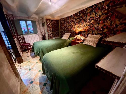two beds in a room with green sheets at Riojania La Posada in Santa Eulalia Bajera