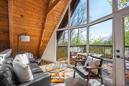 a living room with a couch and chairs and windows at Charming A-Frame Cabin w Hot Tub & Mountain Views in Gatlinburg