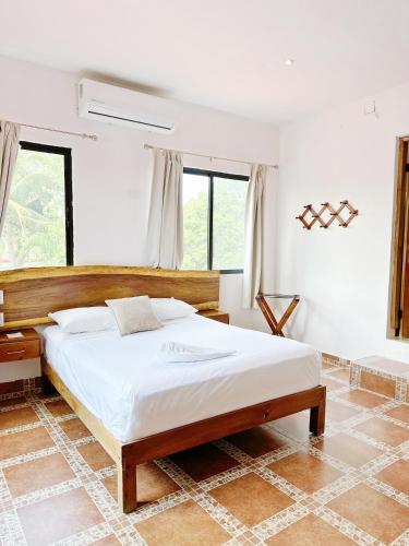 a bedroom with a bed in a room with windows at Hotel El Perico Marinero in Río Lagartos