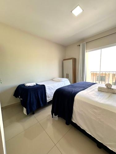 a bedroom with two beds and a large window at Flat Davisis 9 - Parada do Jalapão e Aeroporto in Palmas