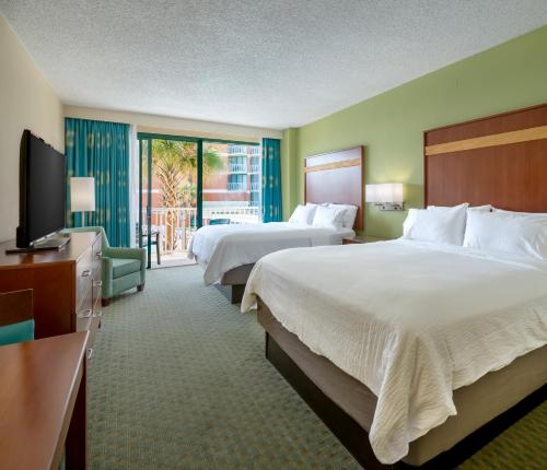 a hotel room with two beds and a flat screen tv at Holiday Inn & Suites Virginia Beach - North Beach by IHG in Virginia Beach