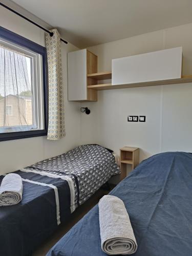 une petite chambre avec deux lits et une fenêtre dans l'établissement Mobil home clim 3 chambres à 100m de la plage, à Canet
