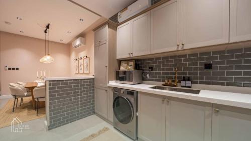 a kitchen with white cabinets and a washer and dryer at نزل سدن in Quai