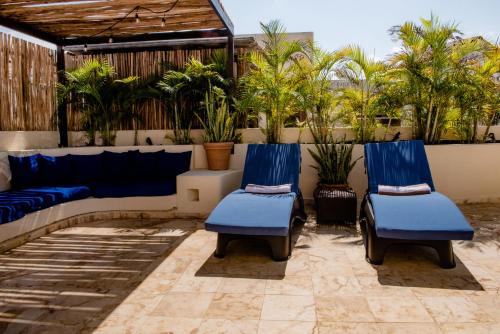 a patio with two blue chairs and palm trees at Porto Playa Condo Hotel and Beach Club in Playa del Carmen