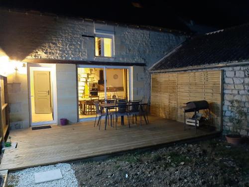 une terrasse en bois avec une table et des chaises sur une maison dans l'établissement Gîte de campagne 4 ou 5 personnes, à Thuré