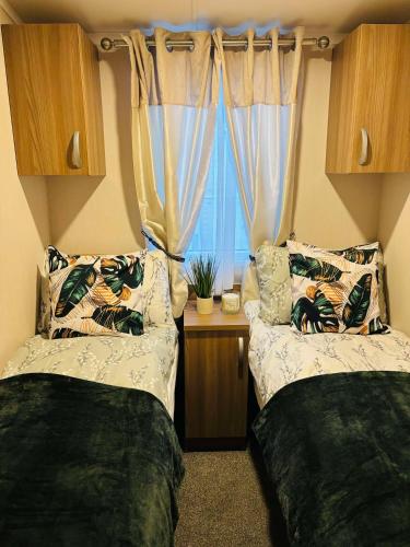two beds in a room with a window at Haven Holiday Park, Kent Coast in Allhallows