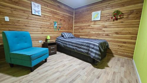 a bedroom with a bed and a blue chair at Lodge playa pupelde, Ancud in Mecura