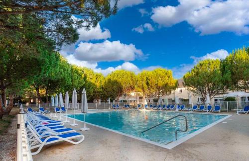 une grande piscine avec des chaises et des parasols bleus dans l'établissement Le petit logis de Lascaux, à Montignac