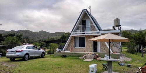 a car parked in front of a house with an umbrella at Cabañas Jazmines del Lago in San Roque