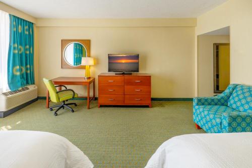 a hotel room with a bed and a tv and a desk at Holiday Inn & Suites Virginia Beach - North Beach by IHG in Virginia Beach