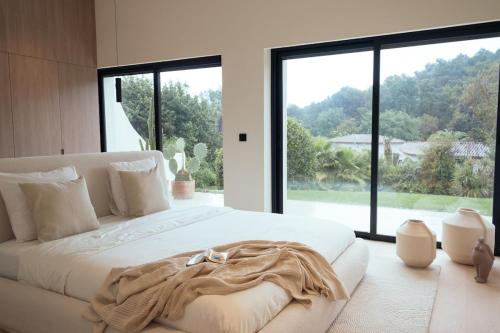 une chambre avec un grand lit blanc avec une grande fenêtre dans l'établissement Villa in Luxury Estate, Mougins, à Mougins