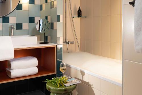 ein Badezimmer mit Dusche und einem Glas Wein in der Unterkunft Yuna Montmartre - ApartHotel in Paris