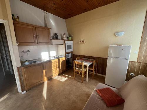 une cuisine avec un réfrigérateur blanc et une table dans l'établissement Aux Roses, à Saint-Honoré-les-Bains