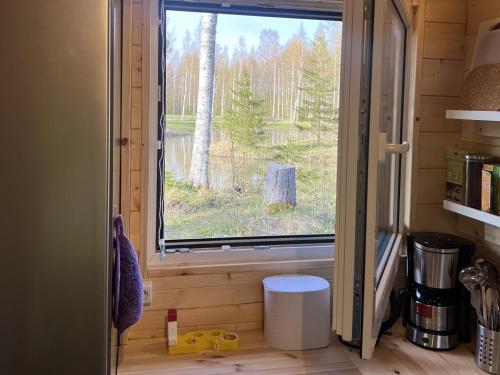 a window in a tiny house looking out at a forest at Marika Puhkeküla - Metsanurga Järvemaja in Nõva