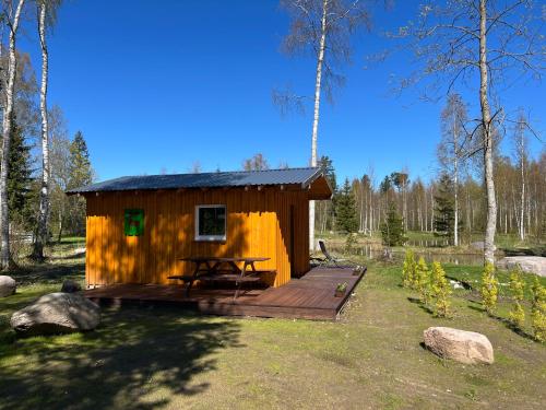 a small wooden cabin with a picnic table on a deck at Marika Puhkeküla - Metsanurga Järvemaja in Nõva