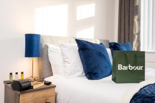 a bed with blue pillows and a green bag on it at Luxury 5 Bed House With Parking in Solihull
