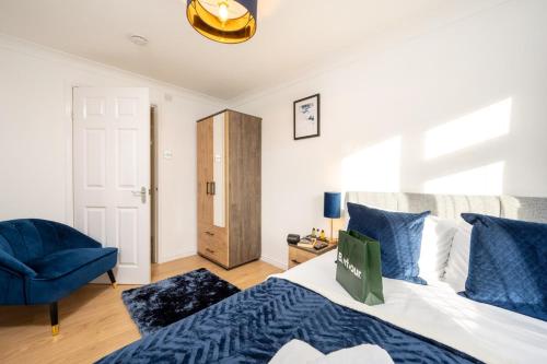 a bedroom with a bed and a blue chair at Luxury 5 Bed House With Parking in Solihull