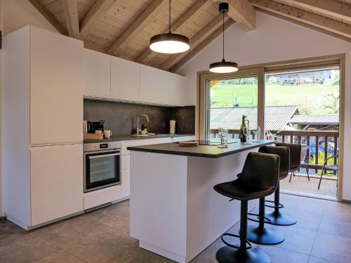 a kitchen with white cabinets and a counter with chairs at Apartment Huus Chloster- Apt Büel by Interhome in Krattigen
