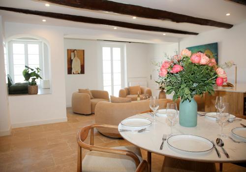 une salle à manger avec une table avec un vase de fleurs dans l'établissement 3BR on the Remparts of Antibes - Sea & Mountain View, à Antibes