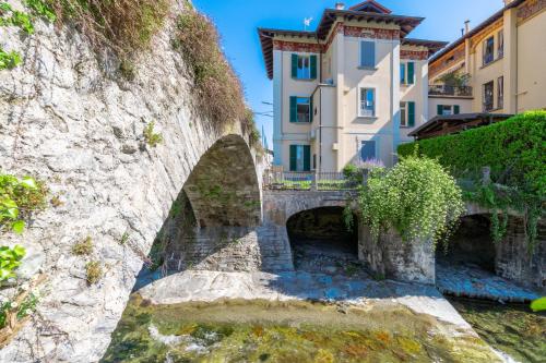 a stone bridge over a river with buildings in the background at Nel Blu in Menaggio