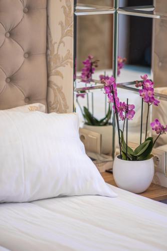 a bed with a white pillow and a vase with flowers at Moris Boutique Beach Hotel in Gdańsk