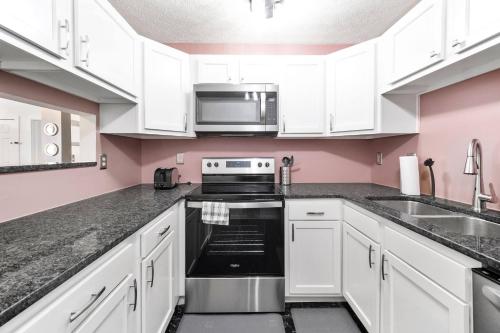 a kitchen with white cabinets and a stove and a microwave at Cozy Condo On Collins- Walk to High St /Dtown /OSU in Columbus
