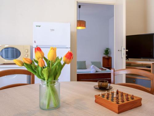 un vase de fleurs sur une table avec un échiquier dans l'établissement Holiday Home Les Gobions by Interhome, à La Bernerie-en-Retz