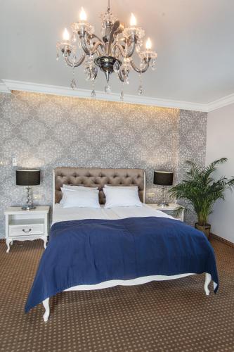 a bedroom with a blue bed and a chandelier at Moris Boutique Beach Hotel in Gdańsk