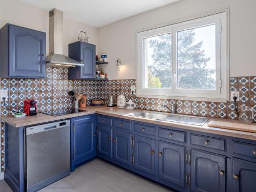 une cuisine avec des placards bleus et une fenêtre dans l'établissement Holiday Home Les Jonquilles by Interhome, à Touques