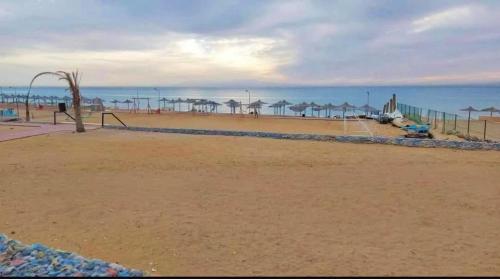 a playground on a beach with the ocean in the background at استوديو مفروش ومكيف في راس سدر -بحر رملي وحمام سباحة- للعائلات الصغيرة فقط in Ras Sedr
