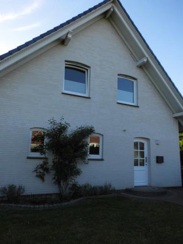 a white house with three windows and a door at Bakumara in Bakum