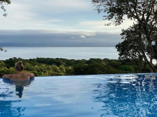 a person in a swimming pool looking out at the ocean at Villas Roma Del Mar in Playa Naranjo