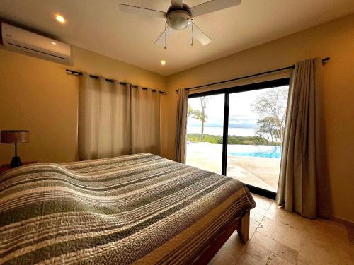 a bedroom with a bed and a large window at Villas Roma Del Mar in Playa Naranjo