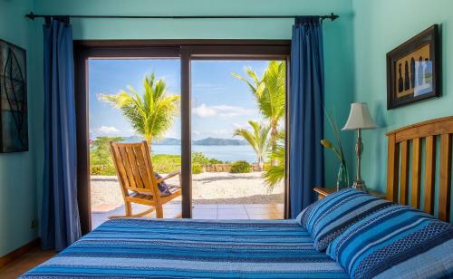 a bedroom with a bed and a view of the beach at Villas Roma Del Mar in Playa Naranjo