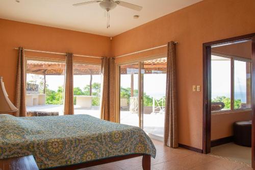 a bedroom with a bed and sliding glass doors at Villas Roma Del Mar in Playa Naranjo