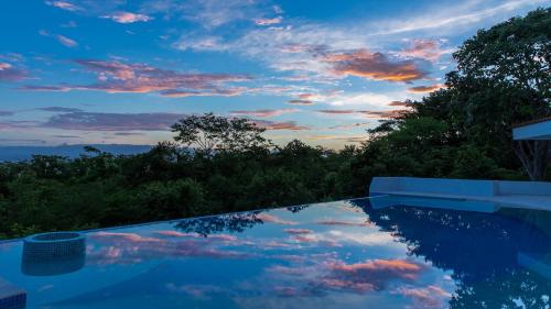 a swimming pool with a cloudy sky in the sky at Villas Roma Del Mar in Playa Naranjo