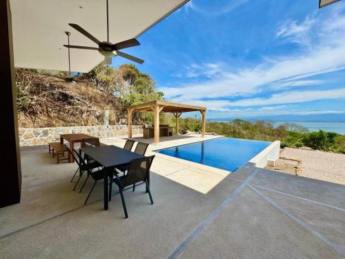 a patio with a table and chairs and a swimming pool at Villas Roma Del Mar in Playa Naranjo