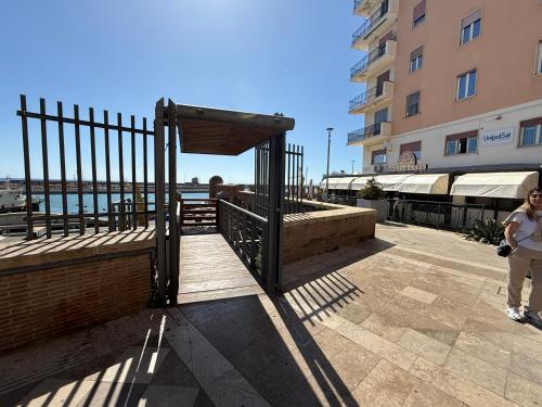 a woman standing next to a fence next to a building at Emy Suites in Civitavecchia