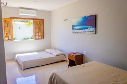 a bedroom with two beds and a window at Belíssima casa na praia do Morro Branco in Beberibe