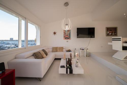a white living room with a white couch and a tv at Modern Apartment in Marina Las Tortugas in Progreso