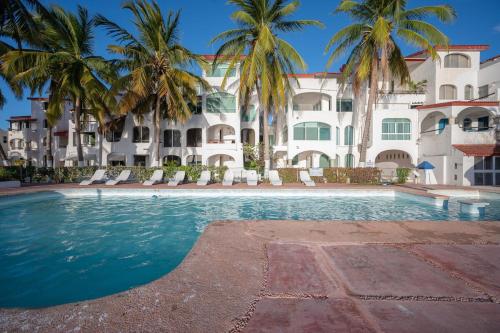 a swimming pool in front of a building with palm trees at Modern Apartment in Marina Las Tortugas in Progreso