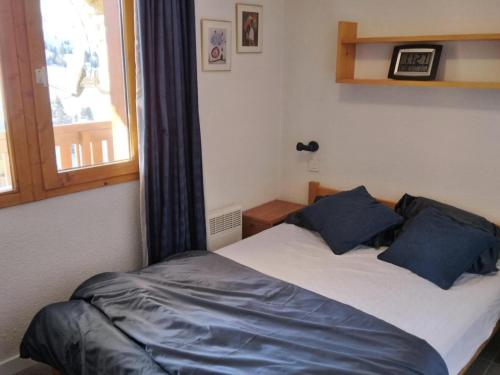 une chambre avec un lit avec des oreillers bleus et une fenêtre dans l'établissement Résidence Carene - 2 Pièces pour 5 Personnes 69, à Mâcot La Plagne