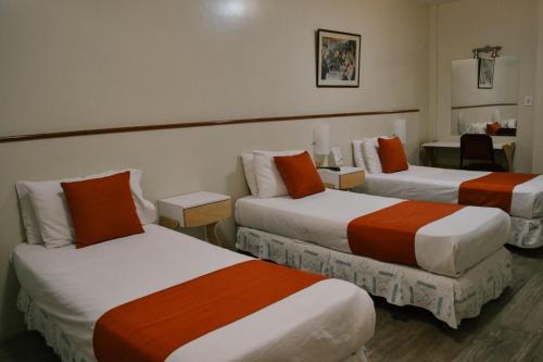 a hotel room with two beds with orange and white at Alpino Hotel in Buenos Aires