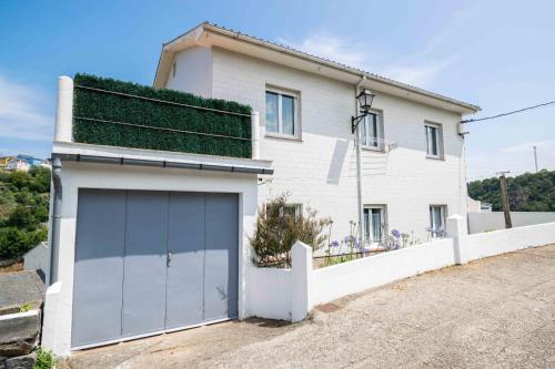 a white house with a garage at Atalaya Luarca Apartamentos turísticos in Luarca