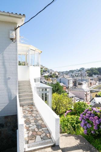 a white house with stairs and flowers at Atalaya Luarca Apartamentos turísticos in Luarca